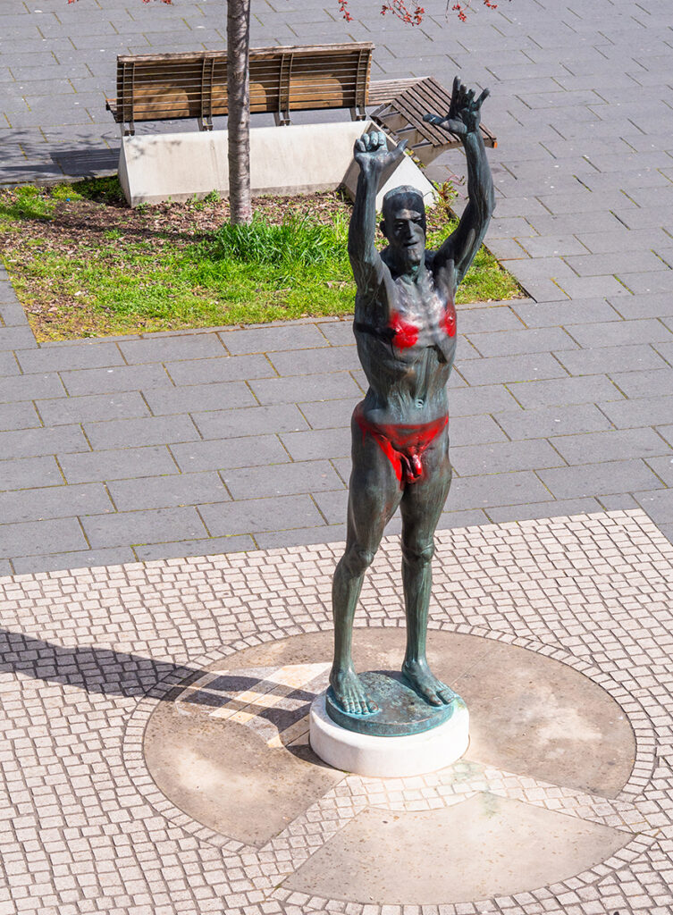 Bronzefigur: nackter Mann hebt seine Hände