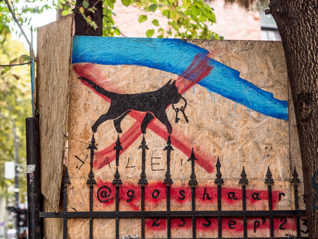 Streetart: schwarze Katze läuft auf Zaun
