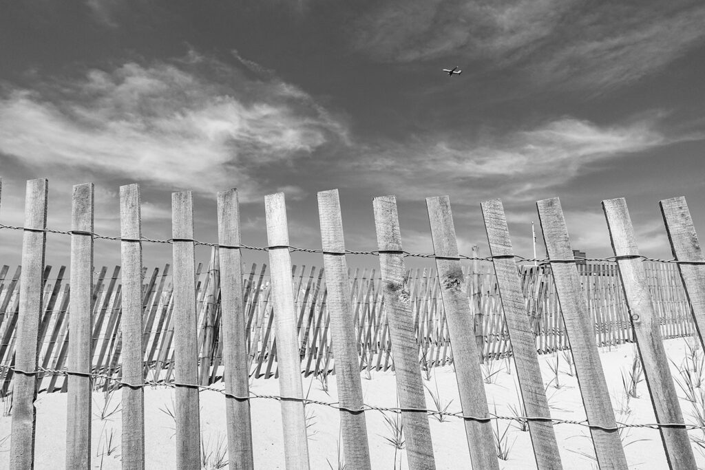 Flugzeug fliegt über Zaun am Strand